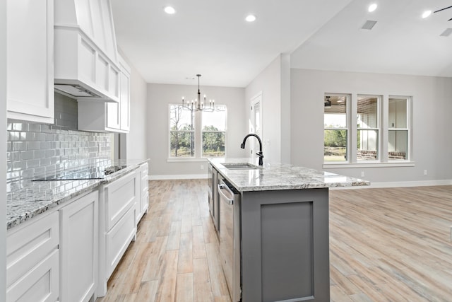 kitchen with a kitchen island with sink, custom exhaust hood, sink, light hardwood / wood-style flooring, and white cabinets