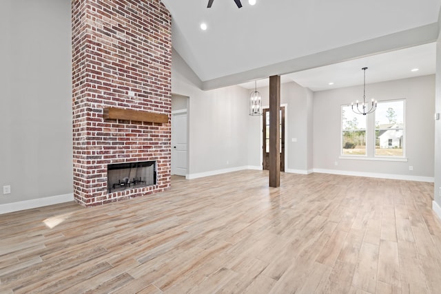 unfurnished living room with brick wall, light hardwood / wood-style flooring, a notable chandelier, and a fireplace