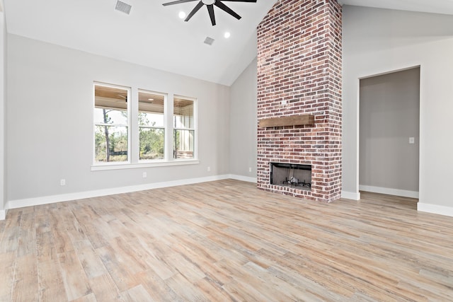 unfurnished living room featuring brick wall, ceiling fan, light hardwood / wood-style flooring, a fireplace, and high vaulted ceiling