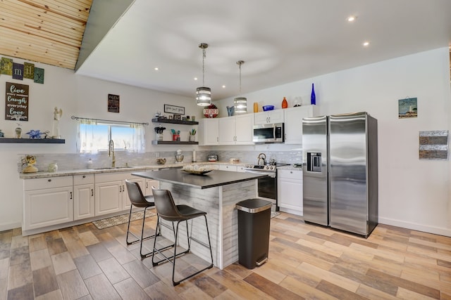 kitchen with white cabinets, a kitchen island, sink, decorative light fixtures, and stainless steel appliances