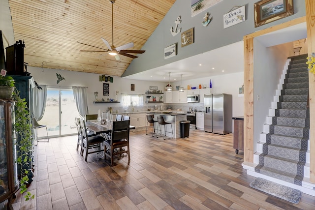 dining room featuring light hardwood / wood-style flooring, high vaulted ceiling, wood ceiling, and ceiling fan