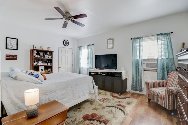 bedroom with ceiling fan, cooling unit, and light wood-type flooring