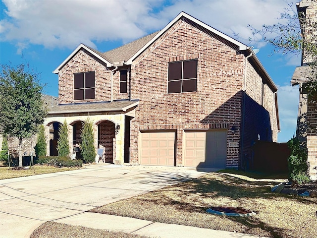 traditional home featuring an attached garage, concrete driveway, and brick siding