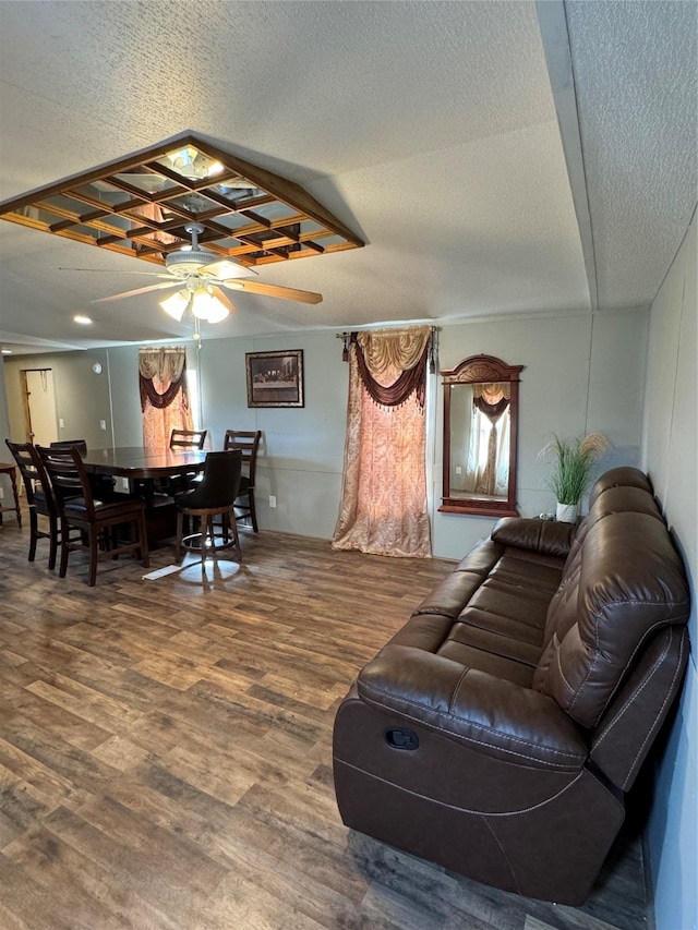 living room featuring ceiling fan, dark wood-type flooring, and a textured ceiling