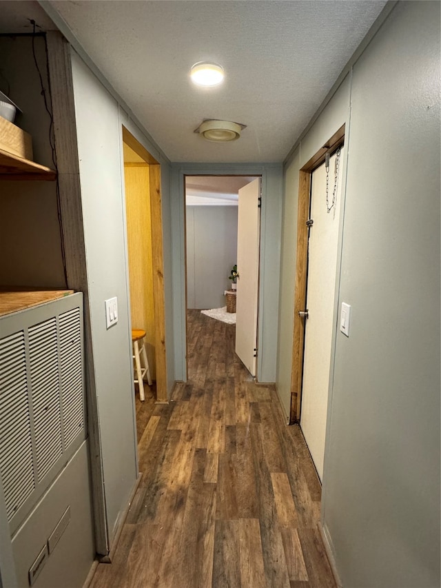 corridor with a textured ceiling and dark hardwood / wood-style floors