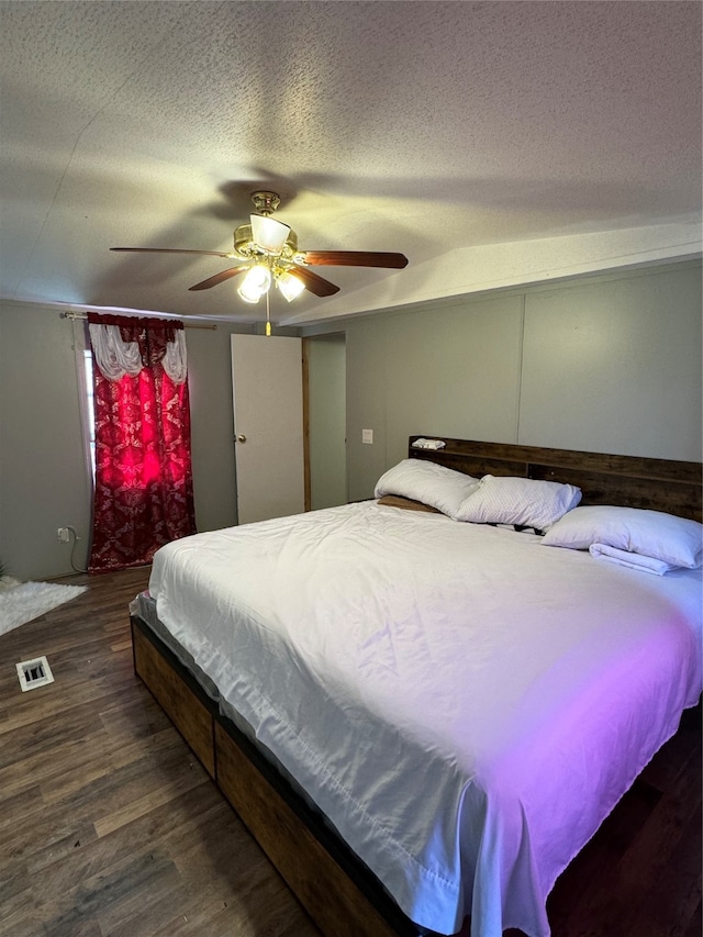 bedroom featuring dark hardwood / wood-style floors, a textured ceiling, and ceiling fan