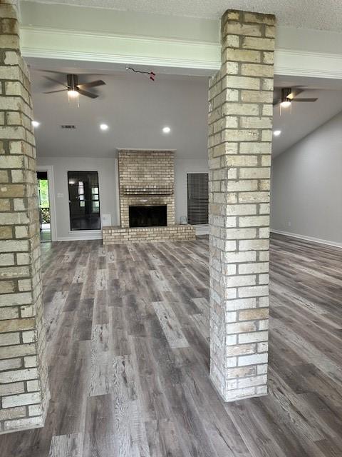 unfurnished living room with a textured ceiling, ceiling fan, a brick fireplace, and hardwood / wood-style flooring