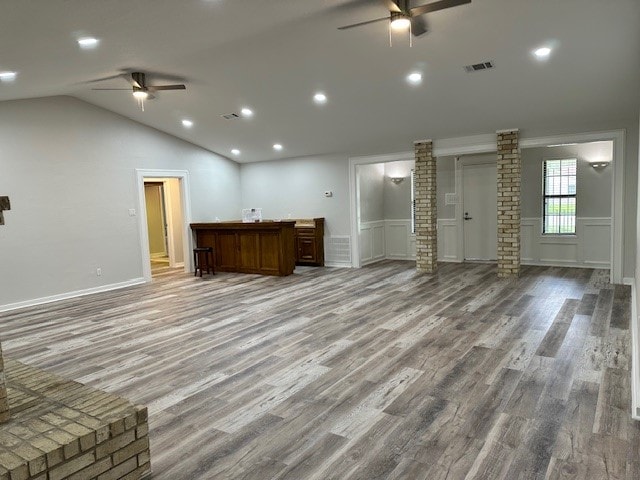 unfurnished living room featuring wood-type flooring, lofted ceiling, ceiling fan, and ornate columns