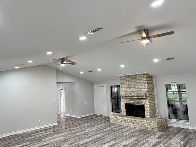 unfurnished living room featuring ceiling fan, hardwood / wood-style flooring, a fireplace, and vaulted ceiling