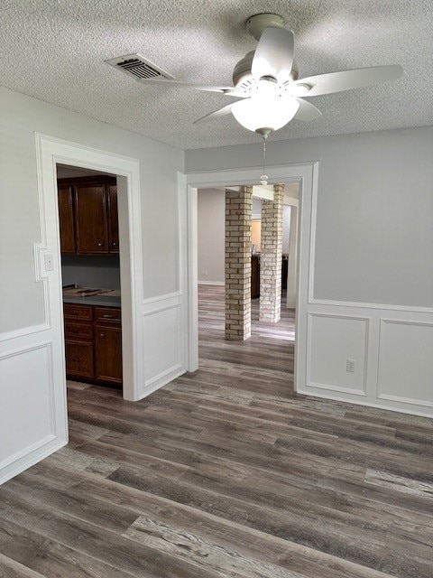 unfurnished dining area with a textured ceiling, ceiling fan, and dark wood-type flooring