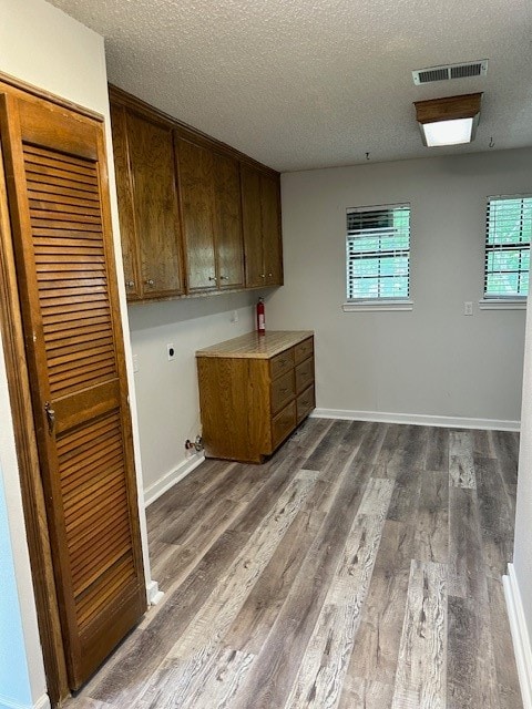 laundry room with cabinets, a textured ceiling, dark wood-type flooring, and hookup for an electric dryer