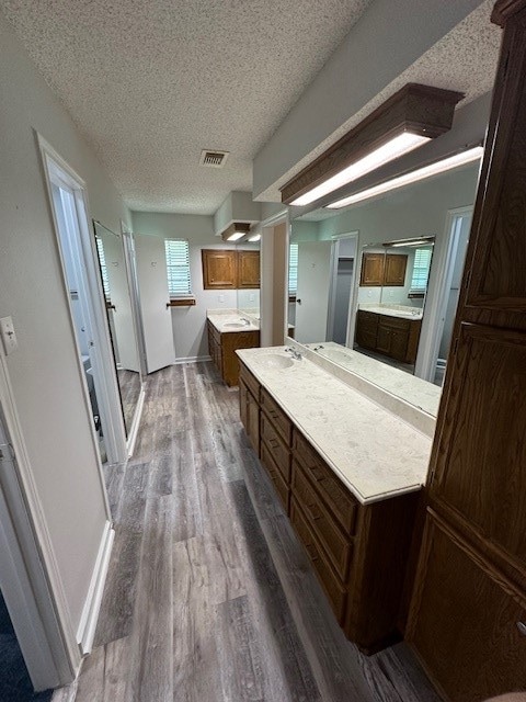 bathroom featuring a textured ceiling, vanity, a bathtub, and hardwood / wood-style flooring