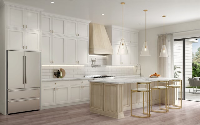 kitchen with paneled fridge, a center island with sink, light hardwood / wood-style floors, custom range hood, and tasteful backsplash