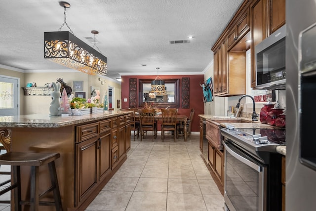 kitchen with stone counters, ornamental molding, stainless steel appliances, and light tile floors