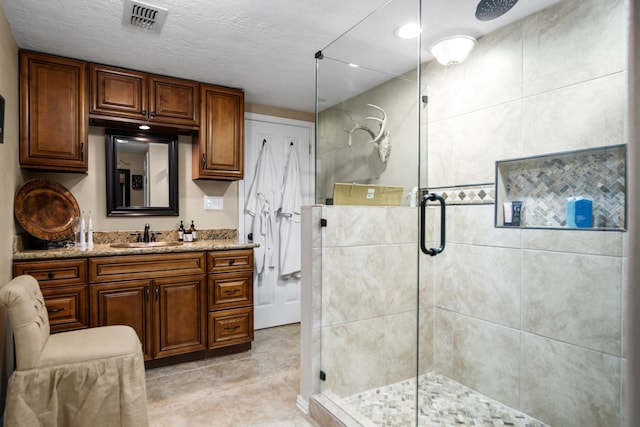 bathroom featuring vanity, a textured ceiling, tile floors, and a shower with shower door