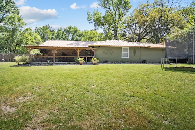 back of property featuring a yard, a trampoline, and a patio area