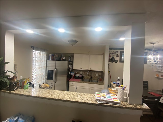 kitchen with white cabinetry, sink, stainless steel refrigerator with ice dispenser, backsplash, and kitchen peninsula