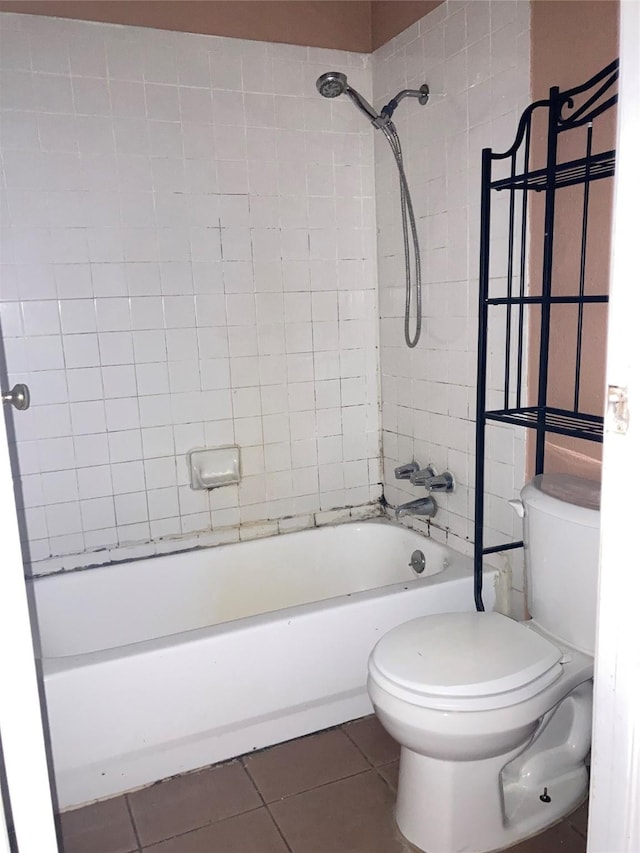 bathroom with tile patterned flooring, toilet, and tiled shower / bath