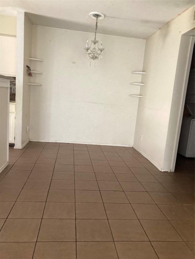 spare room featuring dark tile patterned floors and an inviting chandelier