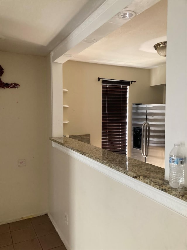 bar featuring dark tile patterned flooring, stone countertops, and stainless steel fridge with ice dispenser