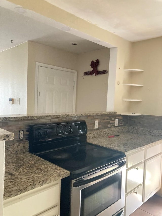 kitchen with white cabinetry, stainless steel electric range oven, tile patterned flooring, and light stone countertops