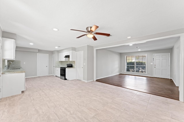 unfurnished living room featuring ceiling fan, light tile floors, and sink