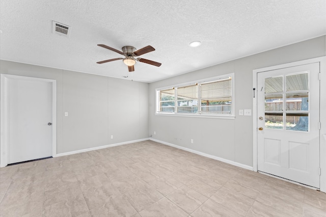 spare room with a textured ceiling, light tile flooring, and ceiling fan