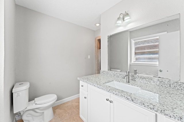 bathroom with toilet, vanity, and tile flooring