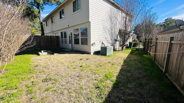 rear view of property featuring central AC and a lawn