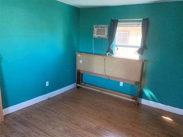 spare room featuring a wall mounted air conditioner and dark wood-type flooring