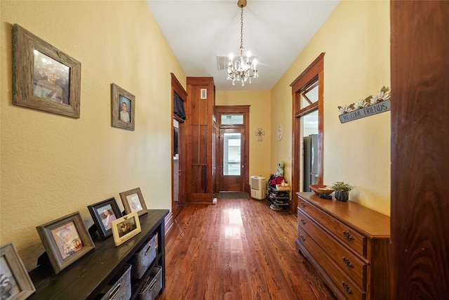 doorway featuring an inviting chandelier and dark wood-type flooring