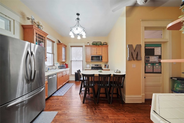 kitchen with appliances with stainless steel finishes, dark wood-type flooring, a breakfast bar, an inviting chandelier, and sink