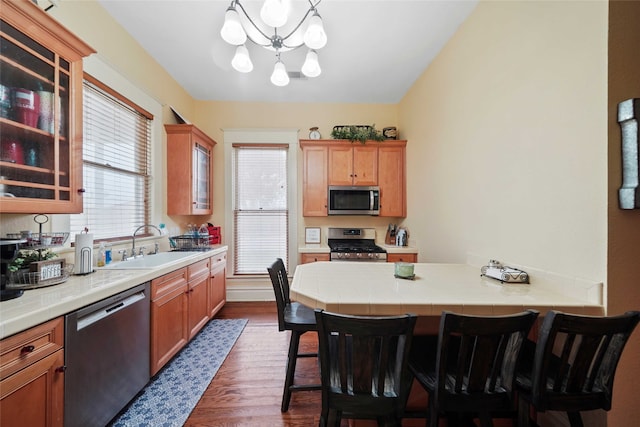 kitchen with dark wood-type flooring, sink, a breakfast bar area, hanging light fixtures, and stainless steel appliances