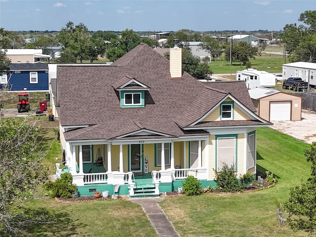 view of front facade featuring a front lawn, an outdoor structure, a garage, and covered porch