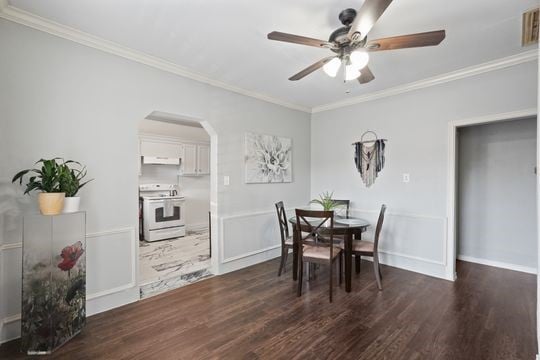 dining space featuring dark hardwood / wood-style floors, ornamental molding, and ceiling fan