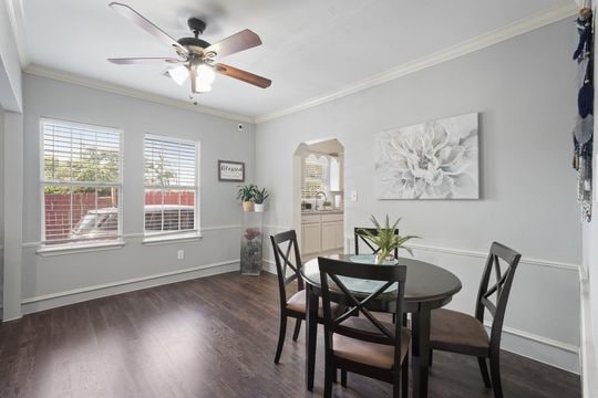 dining area with dark hardwood / wood-style flooring, crown molding, and ceiling fan