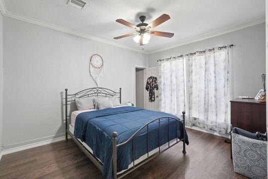 bedroom featuring ceiling fan, dark hardwood / wood-style floors, and crown molding