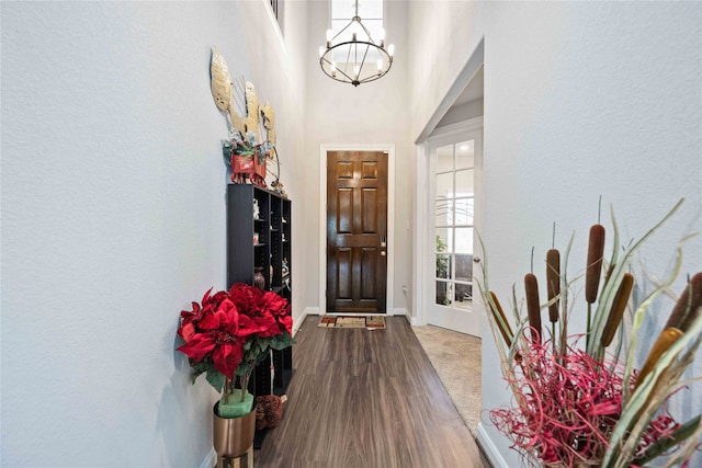 foyer with an inviting chandelier, dark wood-type flooring, and a towering ceiling