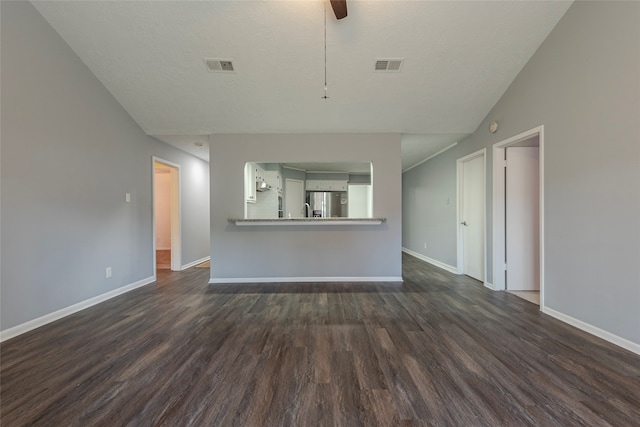 unfurnished living room with lofted ceiling, a textured ceiling, and dark hardwood / wood-style flooring