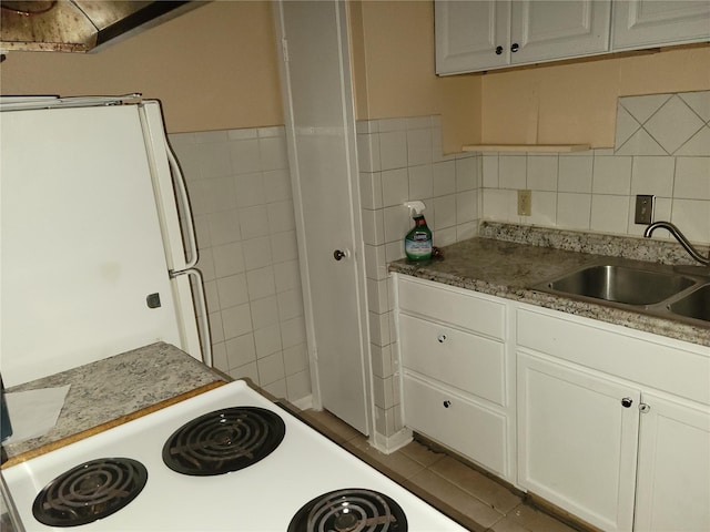 kitchen featuring a sink, tile walls, white cabinets, and tile patterned floors