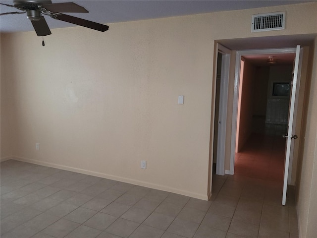 spare room featuring light tile patterned floors, visible vents, ceiling fan, and baseboards