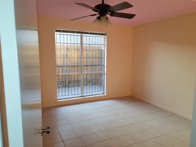 tiled empty room with baseboards and ceiling fan