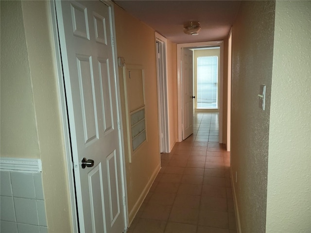 hallway with tile patterned flooring and baseboards