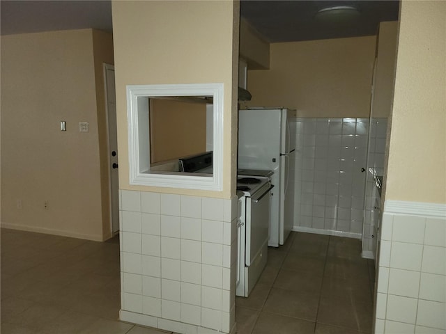 interior space featuring tile patterned floors, tile walls, and electric stove