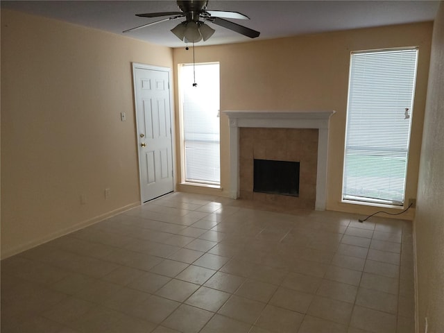 unfurnished living room featuring light tile patterned floors, a tile fireplace, a wealth of natural light, and ceiling fan