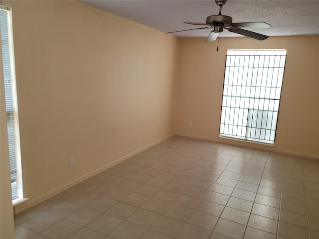 spare room with light tile patterned floors, a textured ceiling, baseboards, and ceiling fan