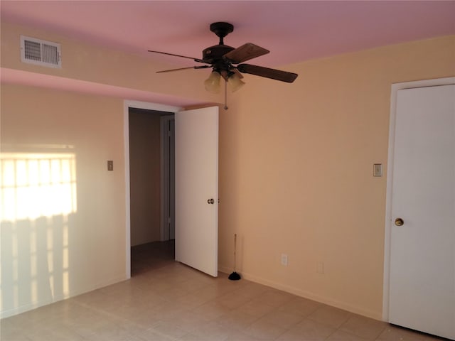 spare room with visible vents, a ceiling fan, and baseboards