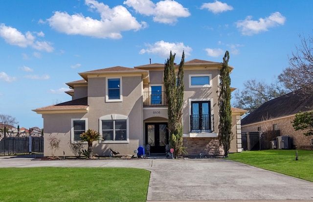 view of front of home with a balcony, a front yard, and french doors