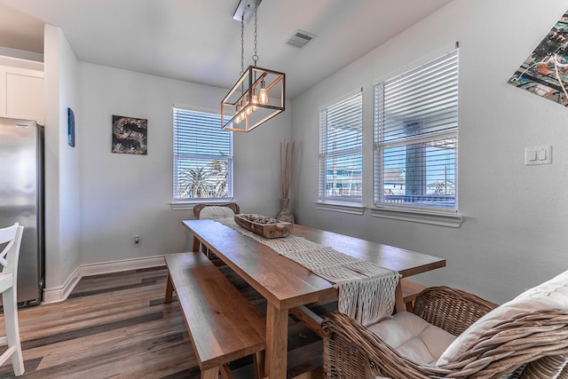 dining area with a healthy amount of sunlight, dark hardwood / wood-style floors, and an inviting chandelier