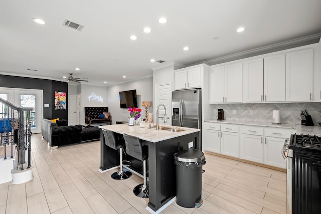 kitchen with light stone countertops, white cabinetry, ceiling fan, and gas range